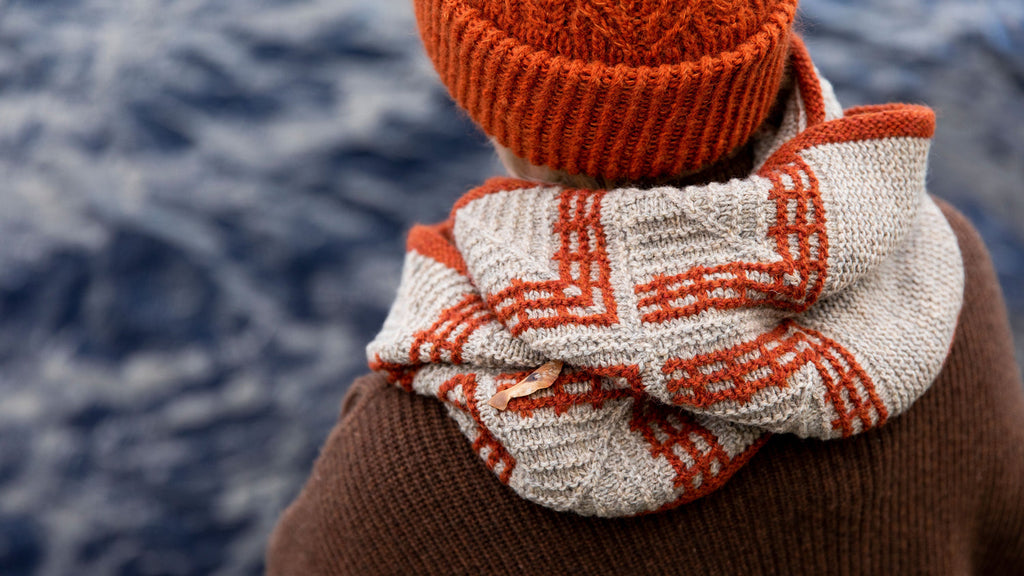 Person wearing a red knitted hat and scarf against a blurred natural background