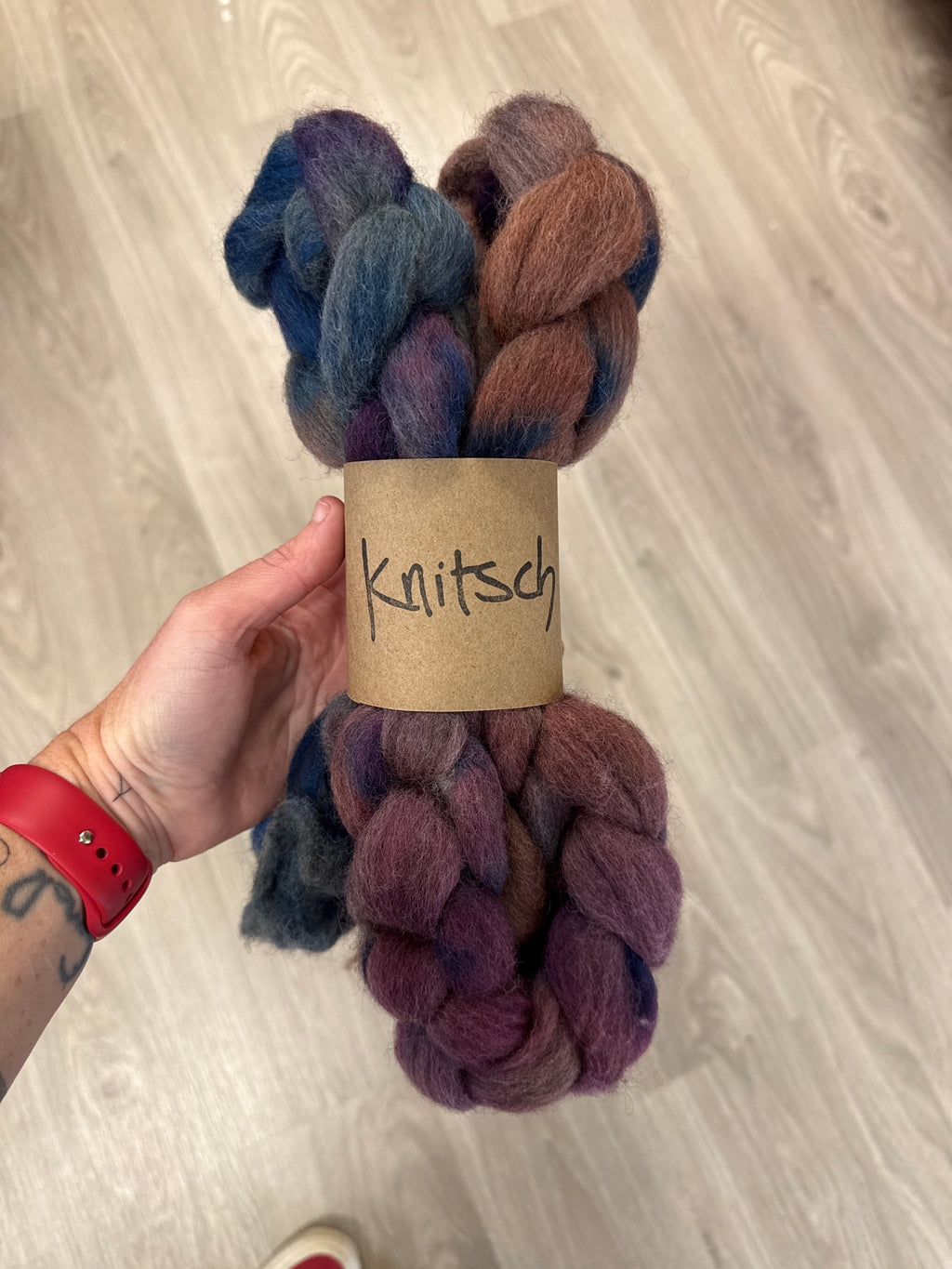 A braid of Knitsch corriedale spinning fibre, in dark blue, pink and brown shades. 
