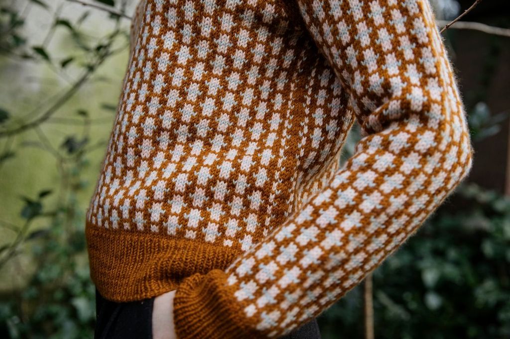 Knitted sweater with a pattern of brown and white on a blurred natural background
