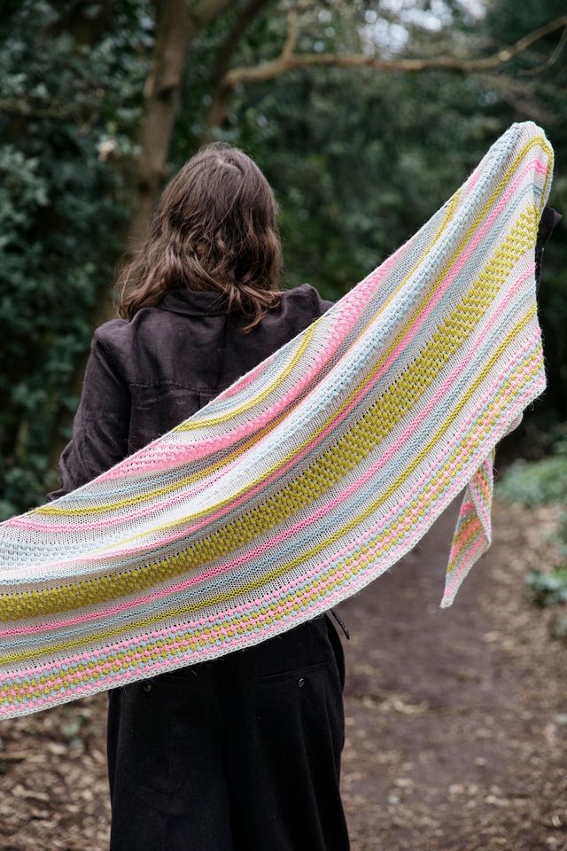 Person holding a colorful striped shawl outdoors