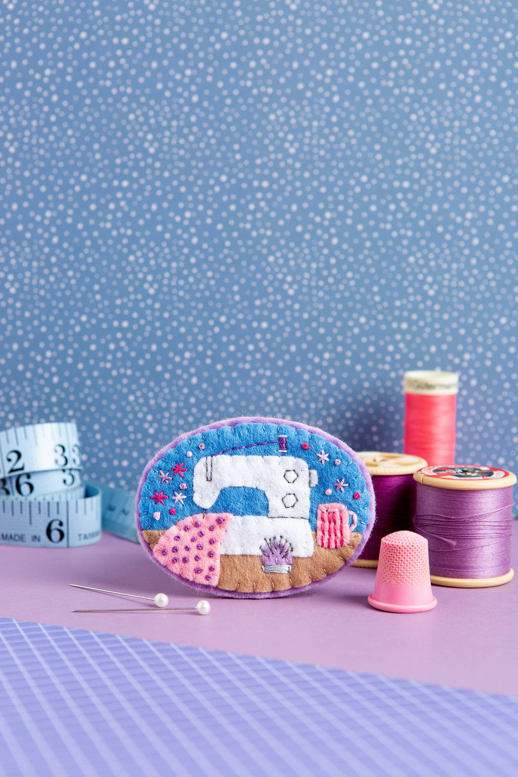 Decorative sewing kit with spools of thread and a thimble on a polka dot background