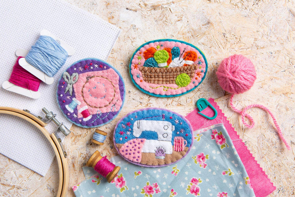 Embroidered patches with sewing-themed designs on a textured surface.