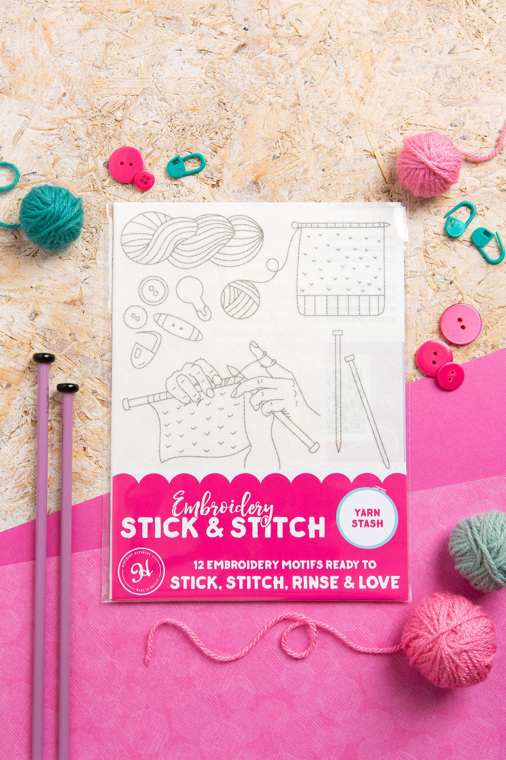 Embroidery design pack with yarn and knitting needles on a textured surface