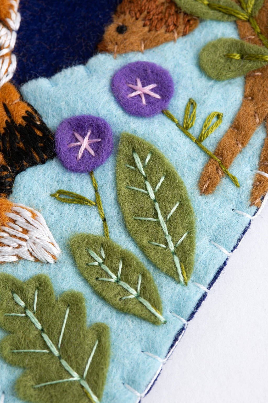 Felted fabric with embroidered animals and plants on a blue background