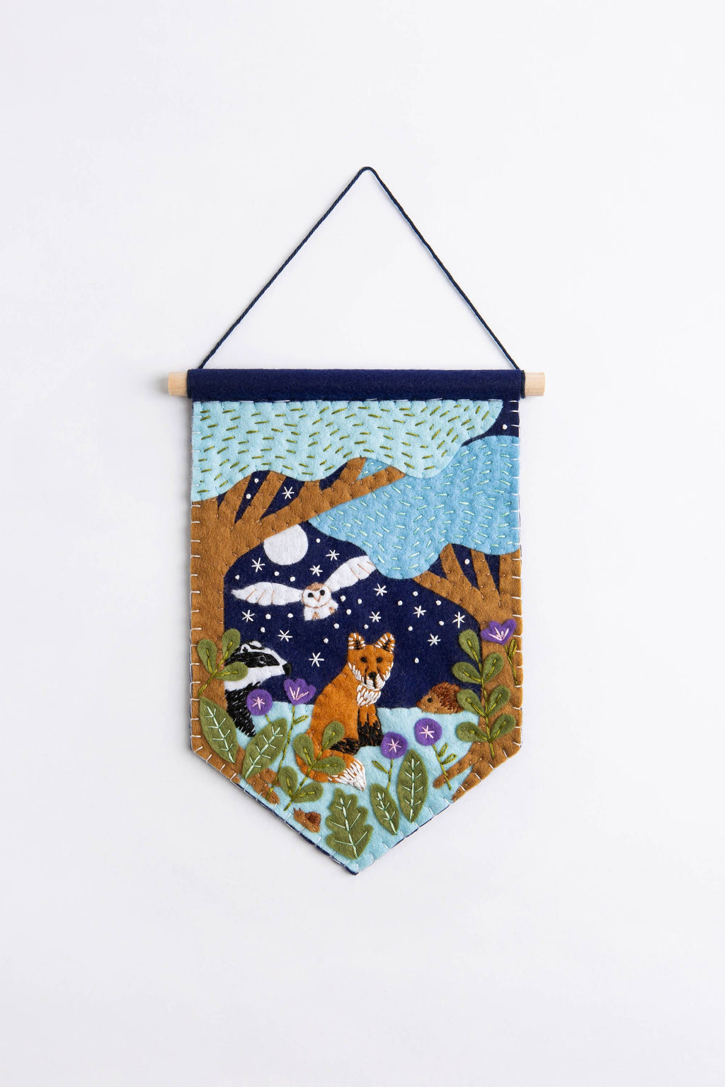 Felt wall hanging with forest scene featuring animals and a moonlit sky.