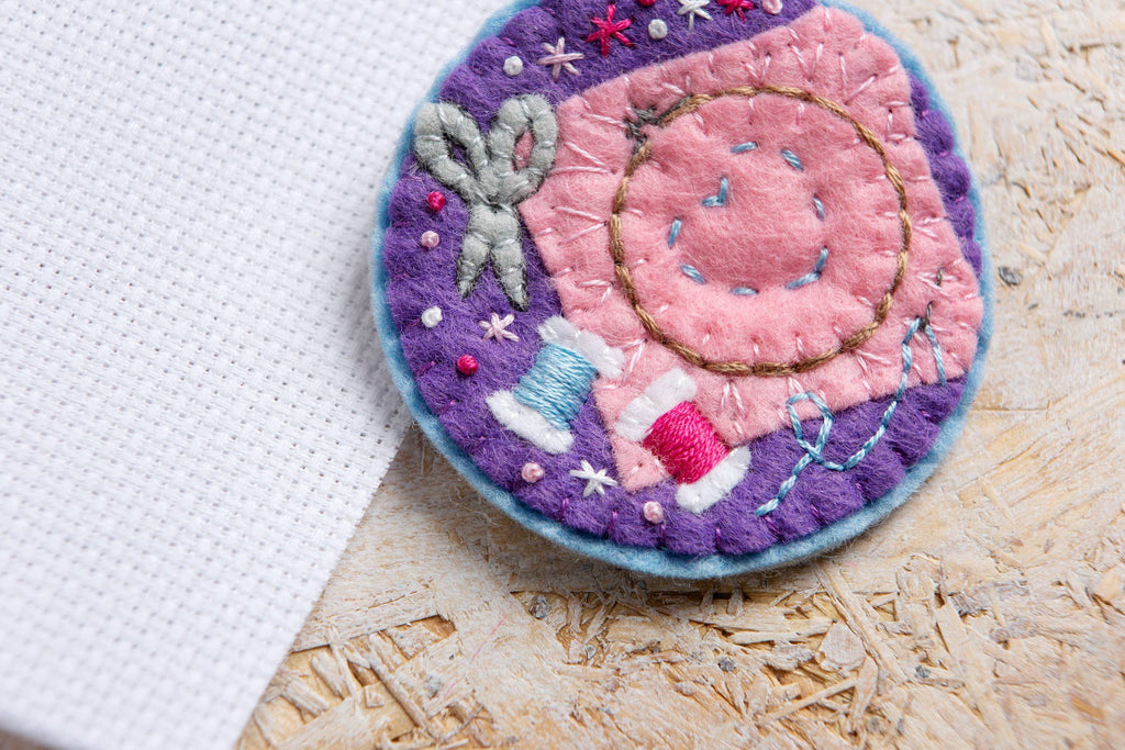 Embroidered patch with sewing-themed design on a wooden surface