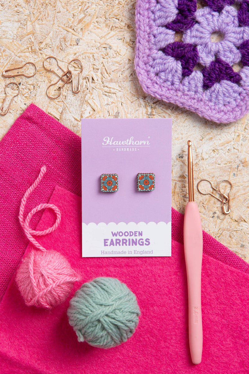 Hawthorn Wooden Earrings packaging with crochet hook, yarn, and purple fabric on a textured surface