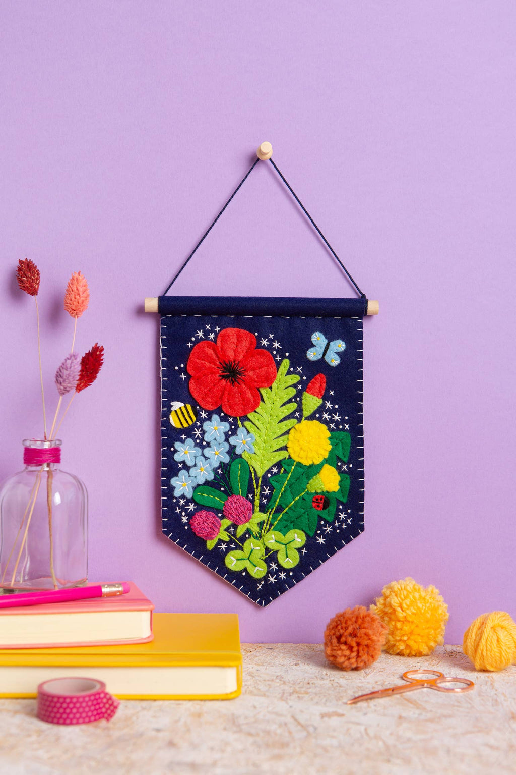 Decorative wall hanging with floral design on a purple wall