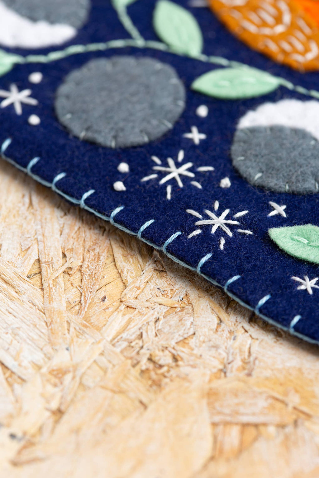 Close-up of a blue embroidered pennant with floral patterns on a wooden surface
