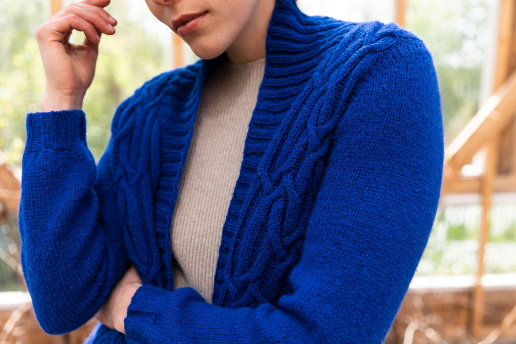 Person wearing a blue knitted cardigan with a blurred background