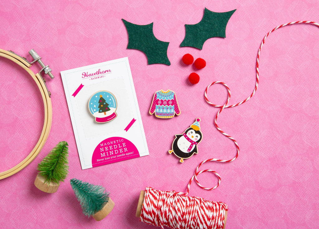 Christmas-themed pins and decorative items on a pink background