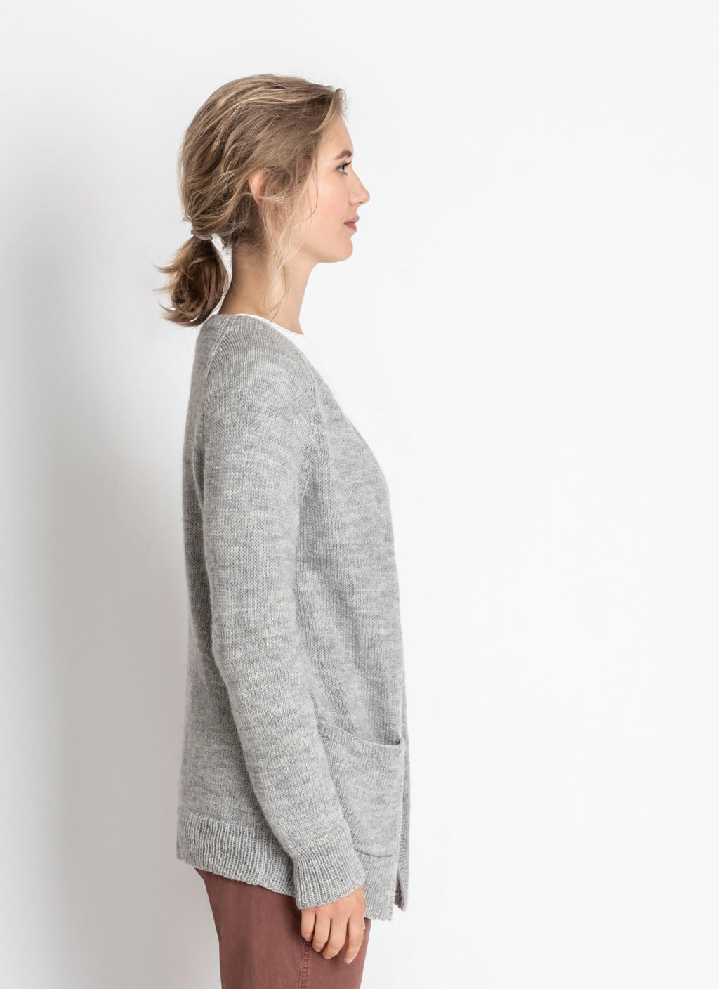 Woman wearing a gray hand knit sweater against a white background