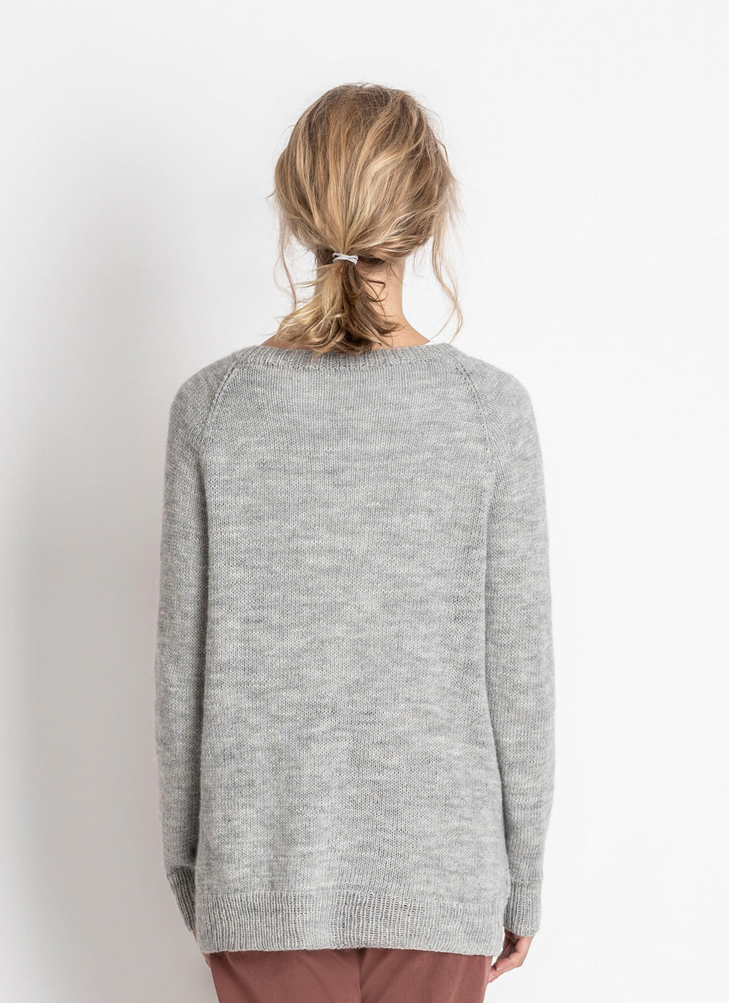 Person wearing a gray hand knit sweater on a white background
