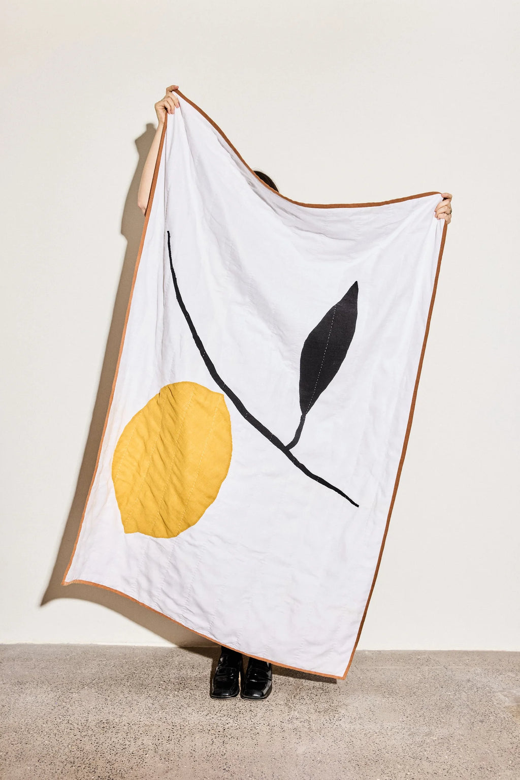 Person holding a white quilt with lemon design